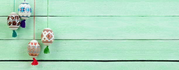 Happy Easter card. Colorful shiny easter eggs on green wooden table background. Copy space for text. Banner