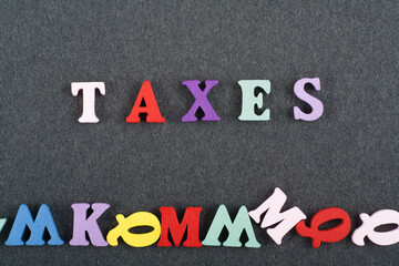 TAXES word on black board background composed from colorful abc alphabet block wooden letters, copy space for ad text. Learning english concept.