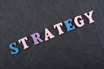 STRATEGY word on black board background composed from colorful abc alphabet block wooden letters, copy space for ad text. Learning english concept.