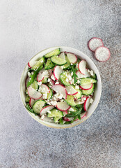 Vegetarian salad of radishes, cottage cheese, sour cream and arugula on a gray background. Top view.