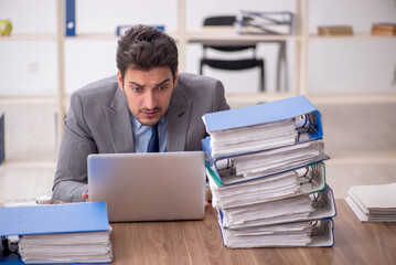 Young male employee and too much work in the office