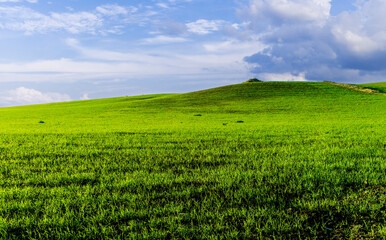 landscape with green grass , country field and beautiful hills and blue sky with clouds