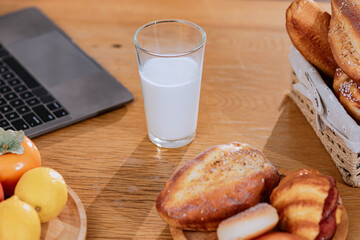 A glass of milk with bread and cooking food on table in the kitchen at home.