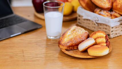 A glass of milk with bread and cooking food on table in the kitchen at home.