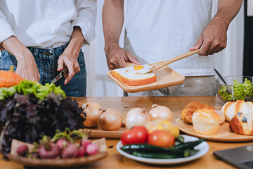 Happy love Asian young man and woman cooking food together in the kitchen relaxing at home.