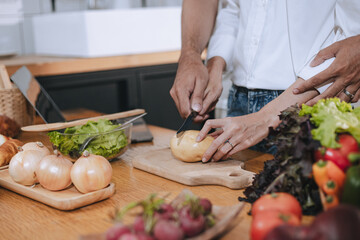 Happy love Asian young man and woman cooking food together in the kitchen relaxing at home.