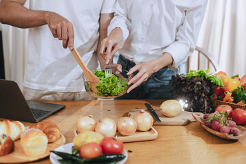 Happy love Asian young man and woman cooking food together in the kitchen relaxing at home.