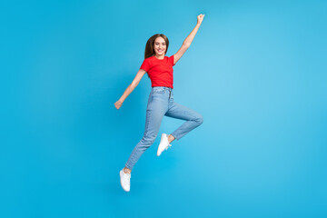 Fototapeta na wymiar Full length photo of glad cheerful funky girl wear red trendy clothes flying forward dream raised hand isolated on blue color background