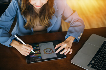 Asian female artist illustrator painting drawing on touch pad digital tablet with stylus pen