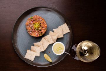 raw salmon tartare with toast sauce and lemon paired with white wine top view