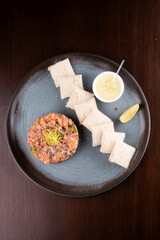 raw salmon tartare with toast sauce and lemon top view