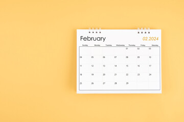 February 2024 desk calendar on yellow color background, position with copy space.