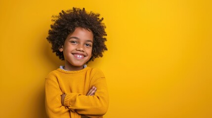 Obraz na płótnie Canvas A boy with curly hair in a yellow sweater on a yellow background. Studio photo of a smiling child 6, 7, 8 years old. Free space