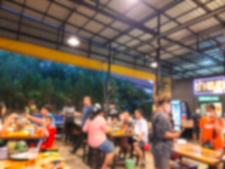 The picture blurs the atmosphere inside a Korean BBQ restaurant with many people eating and coming over.