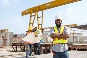 Fototapeta na wymiar African American senior civil engineer or project manager standing and crossed arm with team worker behind at construction site factory produce precast concrete