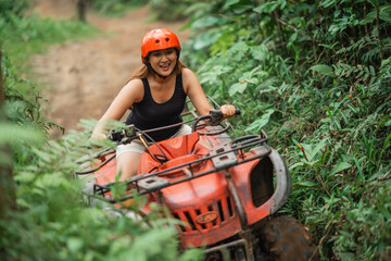 young asian woman riding the atv through the difficult terrain spending her holiday time