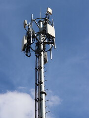Telecommunication tower with antennas against the blue sky background.