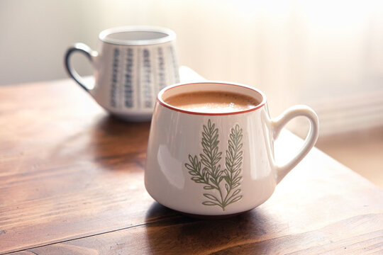 Close-up hot coffee in the morning on wooden table. Two ceramic coffee mugs with smoke on old wooden table. Hot Coffee Drink Concept