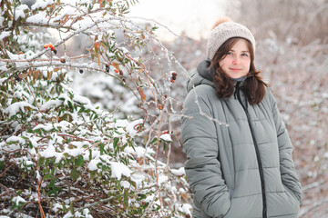 Portrait of young beautiful brunette woman in winter clothes walking on nature