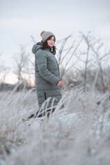 young beautiful woman walking on winter nature, pretty girl in winter clothing on frozen field, rural scene