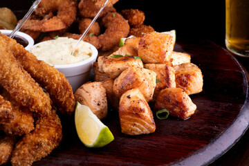 portion of seafood with breaded fish and shrimp and grilled salmon with fries and two glasses of craft beer in close-up
