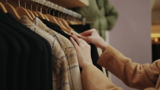 Elegant Businesswoman Shopping In Trendy Clothing Store, Closeup View Of Hands Touching Hangers