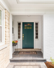 A detail of a front door on home with stone and white brick siding, stone sidewalk, and a colorful blue - green front door.