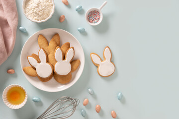 Easter homemade cookies shaped of bunny, sprinkles and sweet chocolate eggs on blue background....