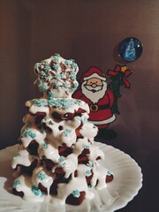 A dessert made of Christmas cookies folded into a Christmas tree, sprinkled with powdered cream and decorated with small snowflakes