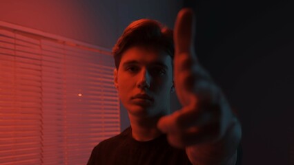 Portrait of male in dark room. Handsome man near window, red neon light shines behind jalousie, guy...