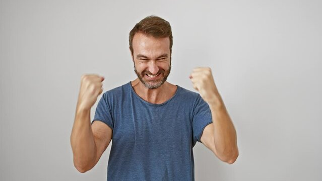 Excited hispanic man in white t-shirt, cheerfully screams in joy, standing proud, arms raised, triumph in expressing emotions of victory, success isolated on white background