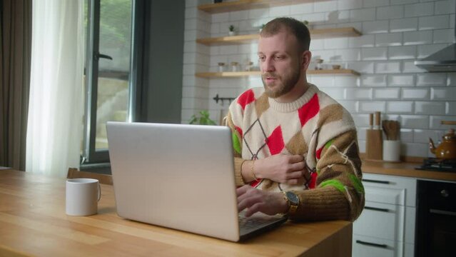 Adult man sit in kitchen suffering chest pain, holding massaging his chest while research to solution on internet with laptop. Male trouble breathing stroke at home. Health problems concept