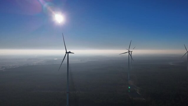 Electricity wind turbine power generator with forest and fog in the background. Aerial shot with drone.