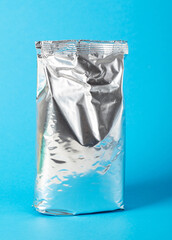 Shiny package with powdered baby milk food on a blue background. Baby formula, close-up