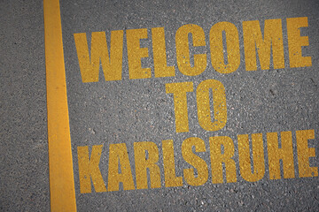 asphalt road with text welcome to Karlsruhe near yellow line.