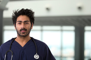 Male Indian healthcare worker wearing a dark blue Scrubs.