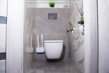View of the interior of a modern bathroom renovation with a hanging toilet bowl, a hygienic shower...