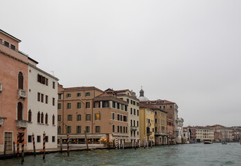Fototapeta na wymiar Facades of weathered buildings with windows on street of Venice city near canal water in daylight