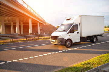 A low-tonnage commercial refrigerated van transports perishable products in the summer on a country...