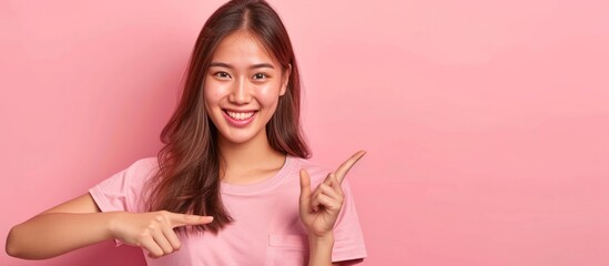 Asian beautiful woman pointing one hands with finger on upper side with smile face on pastel background in studio. copyspace and presentation concept - obrazy, fototapety, plakaty