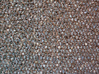 Close-up view of a steel gabion filled with grey and white rocks. The pattern of stone blocks is put into a metallic basket. 