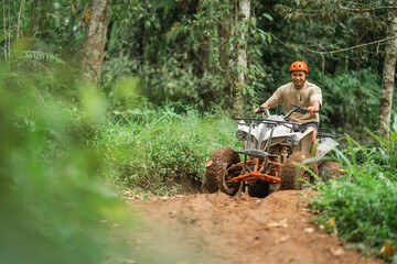 portrait of asian man riding the atv excitedly through the atv track
