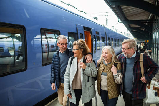 Group of senior friends laughing together at a train station