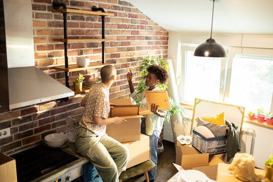 Young lesbian couple decorating new kitchen at home - Powered by Adobe