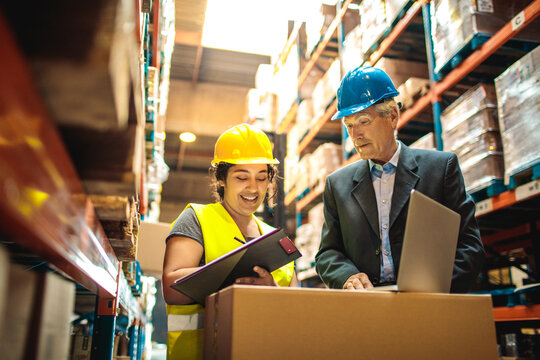 Female warehouse worker and senior male manager reviewing inventory