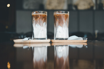 Two iced Mocha coffee two layers fresh milk and espresso short on wooden table at cafe. Refreshing...