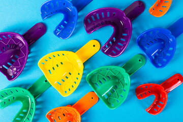 Multi-colored dental spoons for taking an impression of the dental jaw on a blue background....