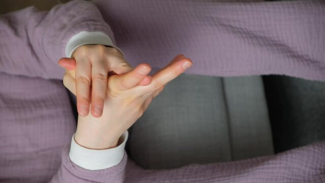 A woman wrings her fingers and cracks her wrists due to stress and anxiety.