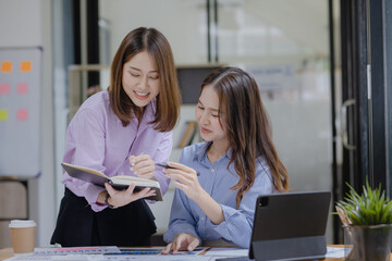 Happy two asian businesswoman working with tablet in meeting room, Businesswoman standing and talking about ideas in office workplace.