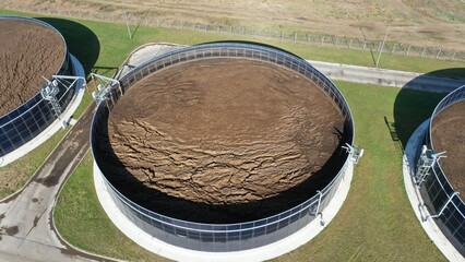 An aerial view of the huge round outdoor manure collection tanks at the dairy farm. Manure collectors on the farm. Manure processing in the open air.